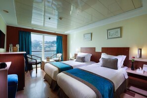 Habitación de hotel con dos camas, un escritorio, una silla y vista a la ciudad.