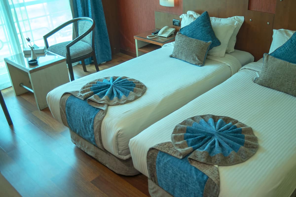A hotel room with two beds, a desk, and a chair.