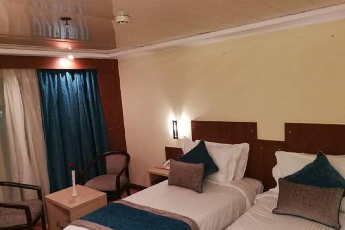 A hotel room with two beds, a desk, a chair, and a nightstand.