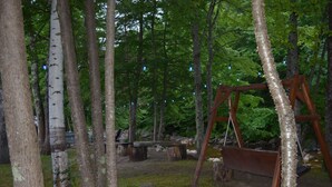 A forested area with a wooden swing set and a bench. - Mount Coolidge Motel (Lincoln)