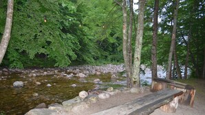A wooden bench by a river with rocks and trees in the background. - Mount Coolidge Motel (Lincoln)