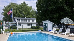 A swimming pool with lounge chairs and a small shed, surrounded by a fence and trees. - Mount Coolidge Motel (Lincoln)