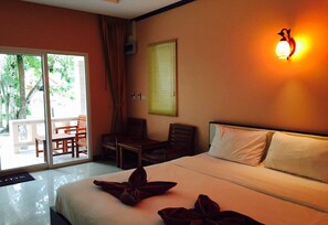 A hotel room with a bed, a desk, and a chair. There is a window with curtains, a wall-mounted light, and a view of the outdoors. - Ao Thong Beach Bungalows & Restaurant (Takua Pa)