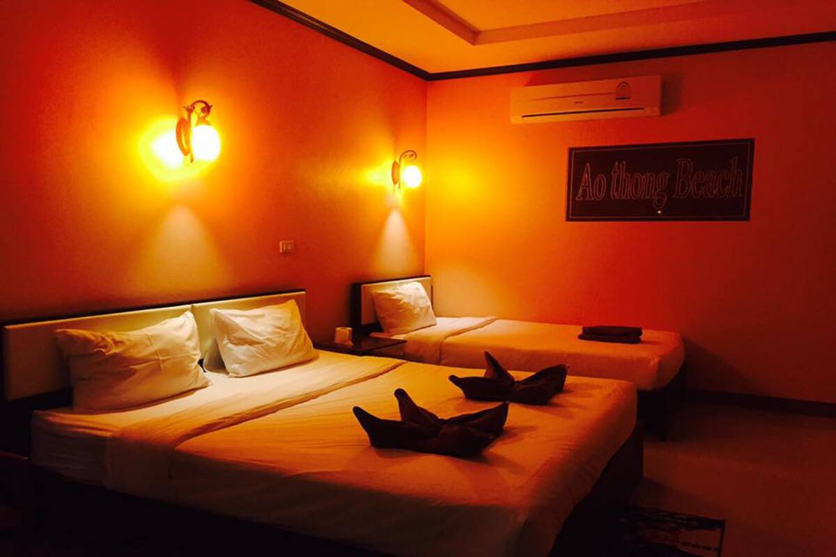 A room with two beds, each with white linens and pillows, and two wall-mounted light fixtures.