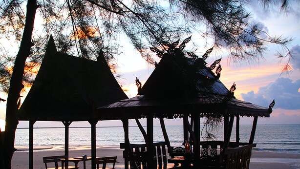 A beach scene with thatched-roof structures and wooden furniture. - Ao Thong Beach Bungalows & Restaurant (Takua Pa)