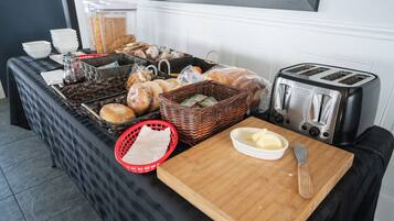 Un buffet della colazione con diversi cibi, un tostapane e un tagliere con un coltello.