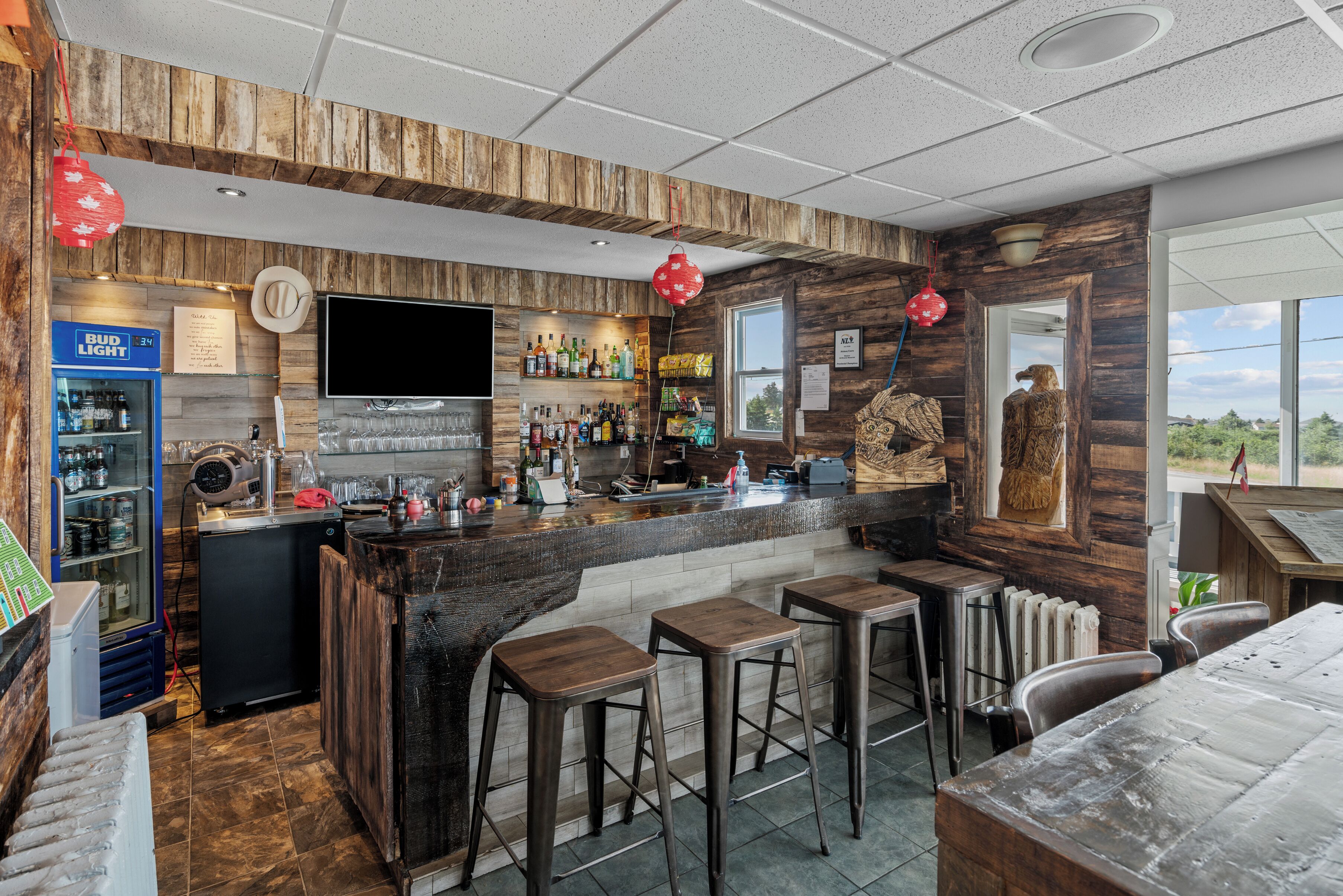 Un área de bar con taburetes, un refrigerador y un televisor.