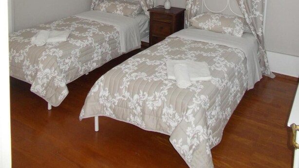 Une chambre avec deux lits simples, une table de chevet, une lampe et un ventilateur de plafond.