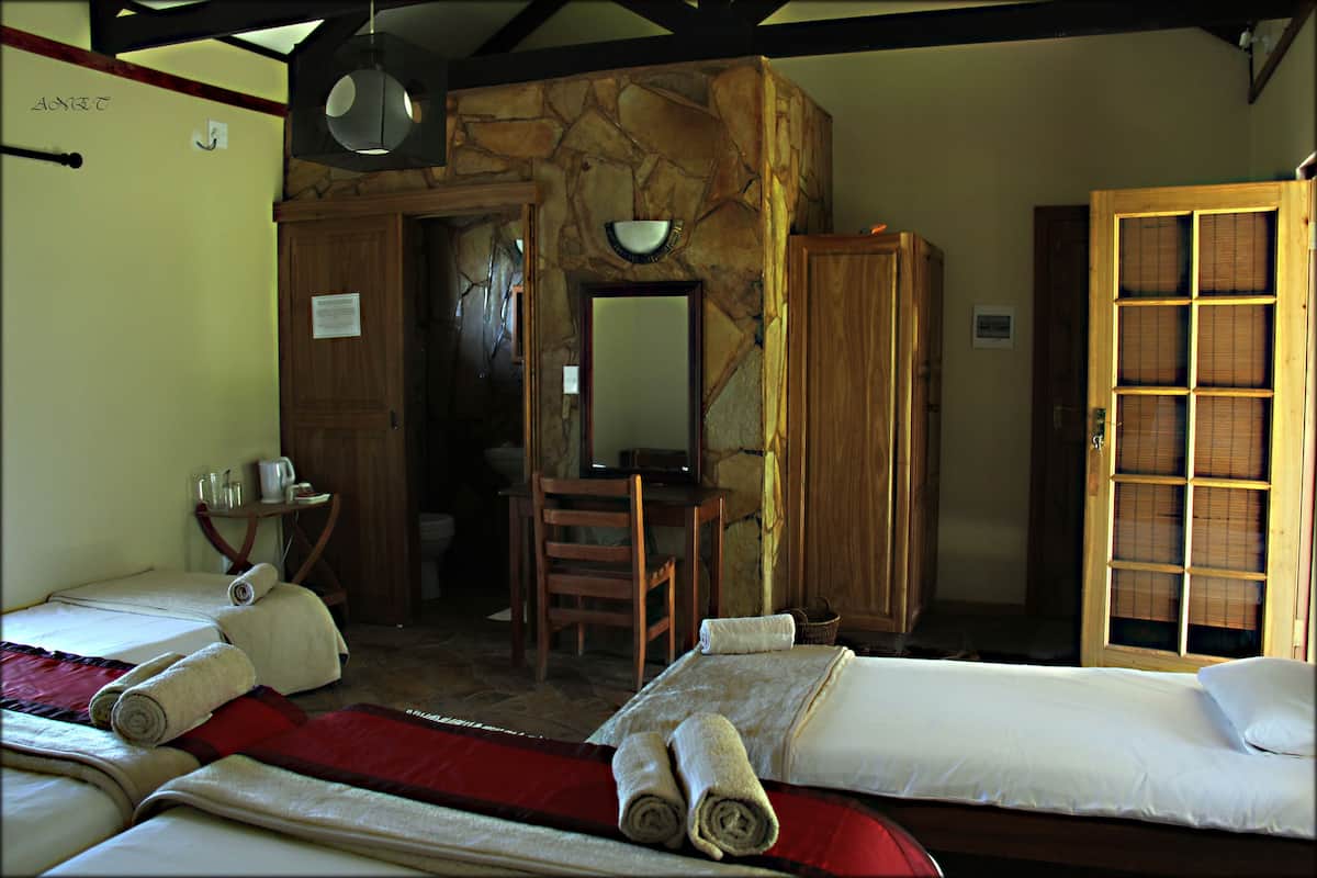 A hotel room with two beds, a desk, a chair, a mirror, and a wardrobe.