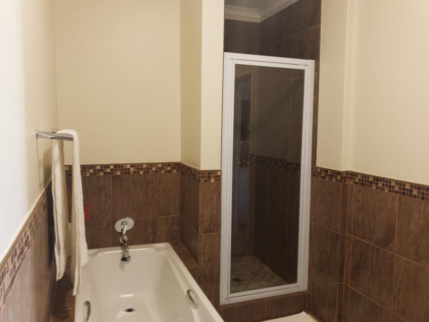 A bathroom with a bathtub, a shower enclosure, and a towel rack.