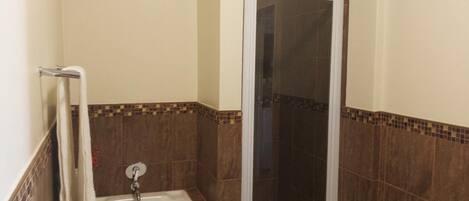 A bathroom with a bathtub, a shower enclosure, and a towel rack.