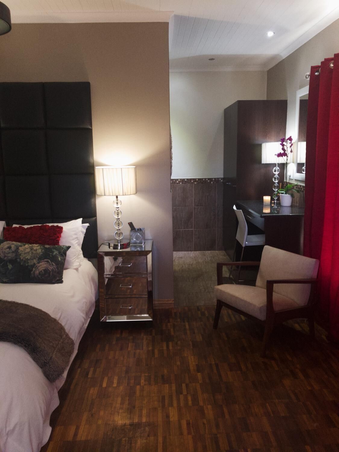 Ein Hotelzimmer mit Bett, Nachttisch, Schreibtisch, Stuhl und Spiegel.