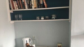 A small, white desk with a wooden chair, a bookshelf above it, and a small refrigerator to the left. - Belvedere BnB (Dublin)