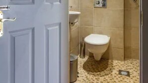 A bathroom with a toilet, sink, and tiled floor. - Belvedere BnB (Dublin)
