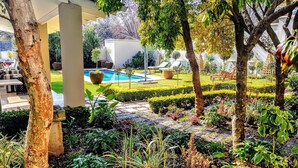 A well-maintained garden with a pool, neatly trimmed hedges, and a variety of plants. - Q on First (Johannesburg)