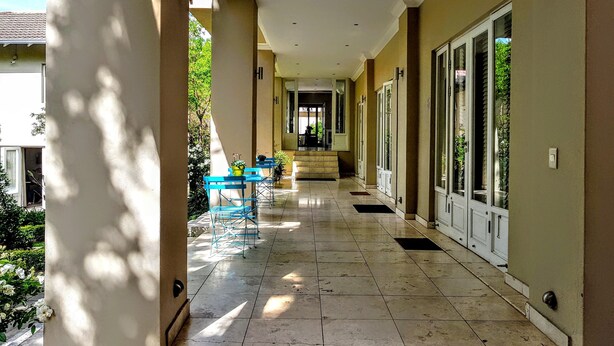 A corridor with a tiled floor, blue chairs, and potted plants. - Q on First (Johannesburg)