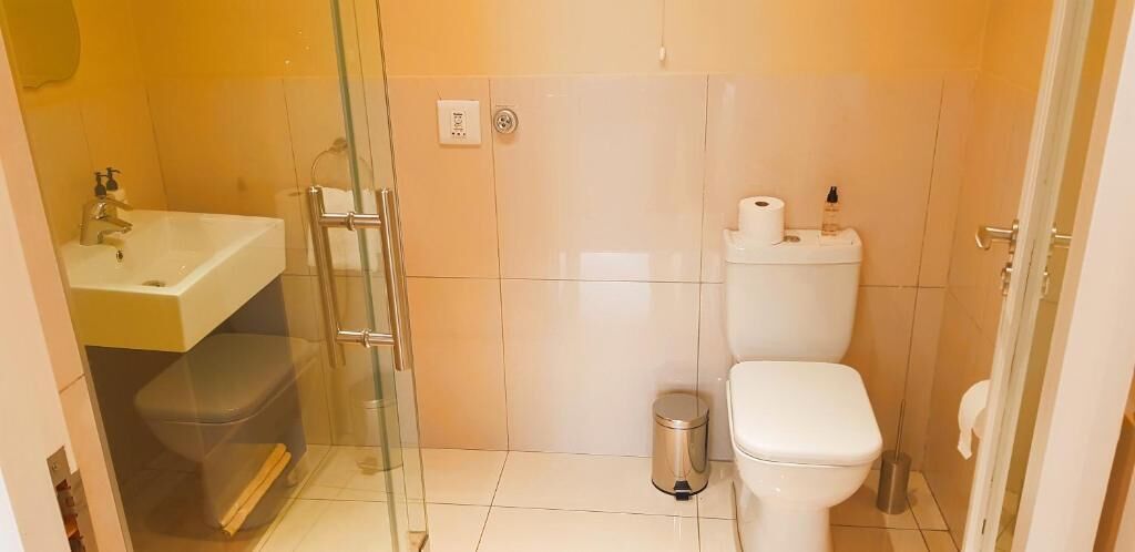 A compact bathroom with a glass shower enclosure, a white sink, and a toilet.