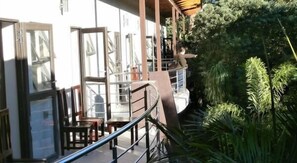 A balcony with a glass railing overlooking a lush garden.
