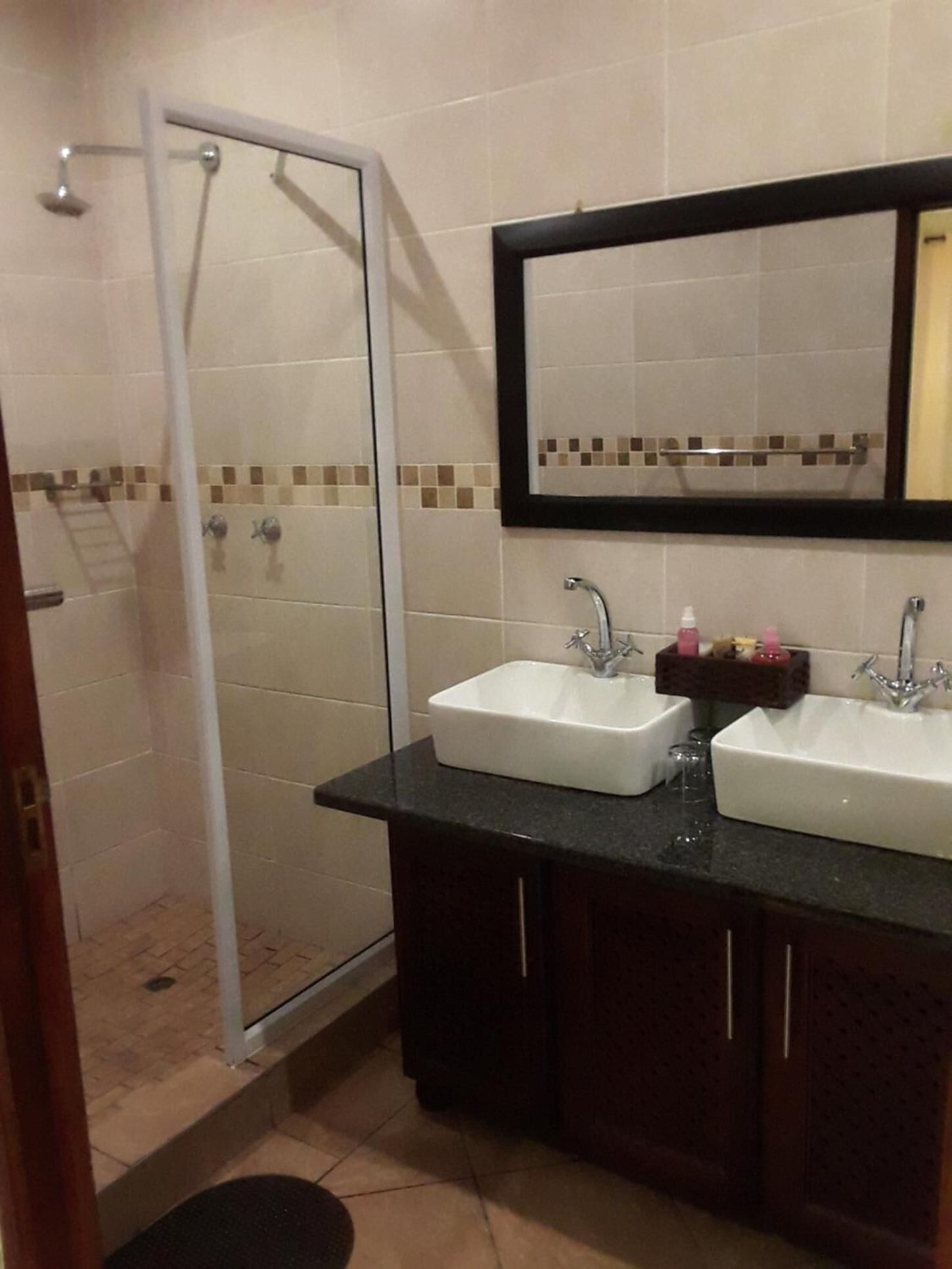 A bathroom with two sinks, a shower, and a large mirror.