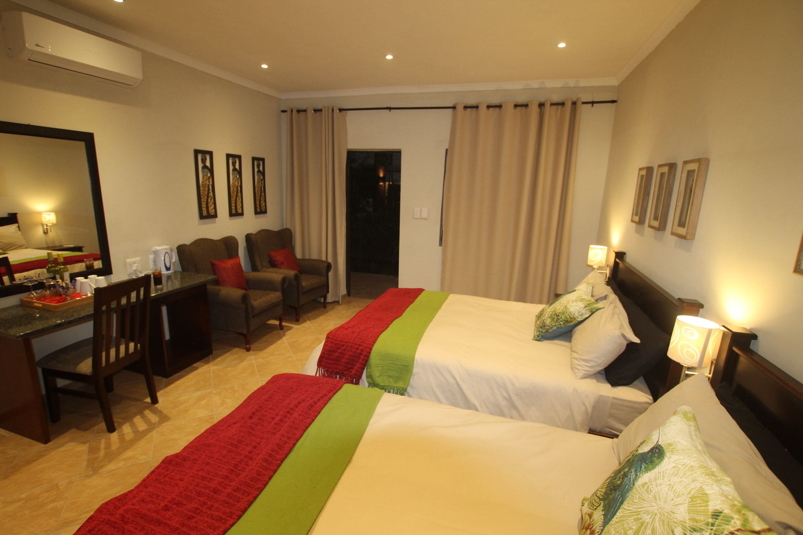 Habitación de hotel con dos camas, un escritorio, una silla y un espejo.