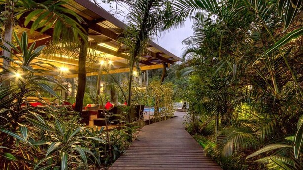 A wooden pathway leading to a building with outdoor seating and lush tropical plants. - Forest Villas (St. Lucia)
