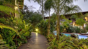 A wooden pathway surrounded by lush greenery leading to a pool area. - Forest Villas (St. Lucia)