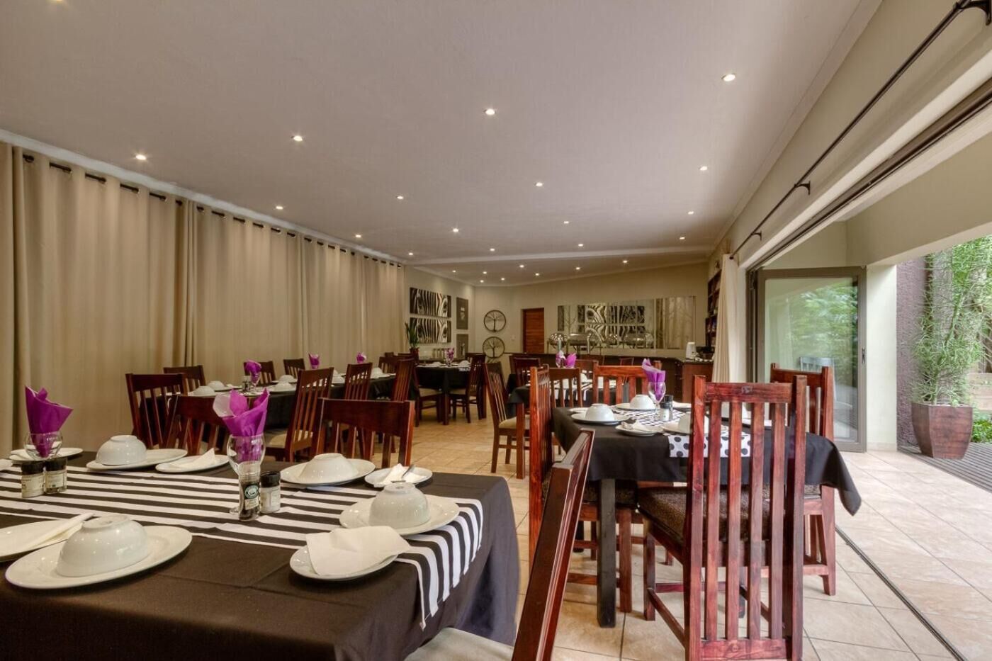 A dining area with tables set for a meal, featuring striped tablecloths and white dinnerware.