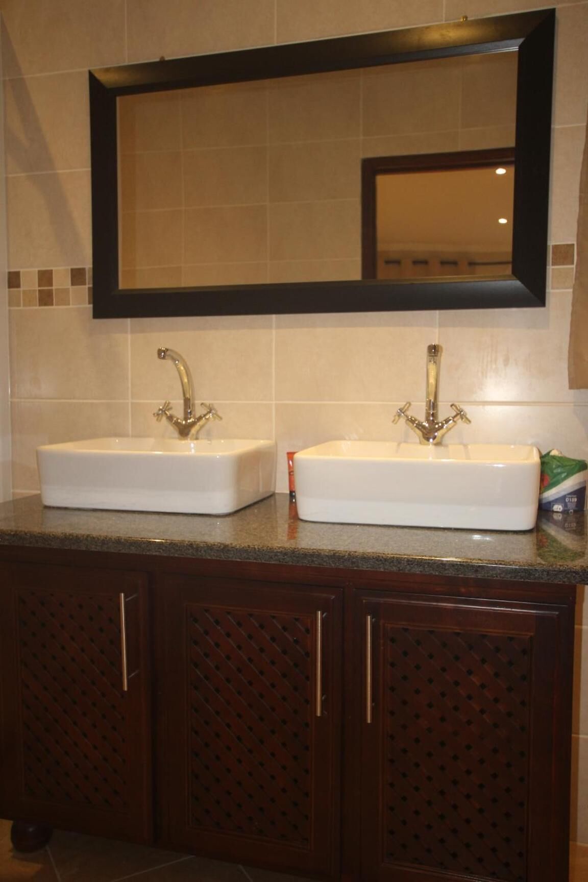 Un baño con dos lavamanos, un espejo grande y armarios de madera oscura.