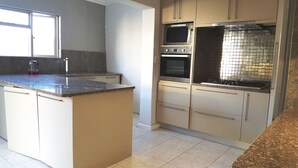 A kitchen with a granite countertop, stainless steel appliances, and beige cabinetry. - 7 on Disa Self-catering Accommodation (Cape Town)