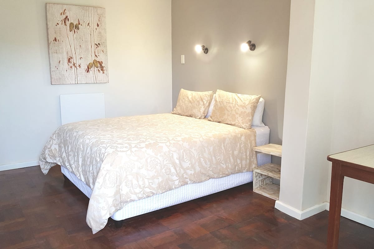 Une chambre à coucher comprenant un lit, des tables de chevet, une commode et un luminaire fixé au mur.