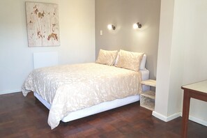 A bedroom with a bed, bedside tables, a nightstand, and a wall-mounted light fixture. - 7 on Disa Self-catering Accommodation (Cape Town)