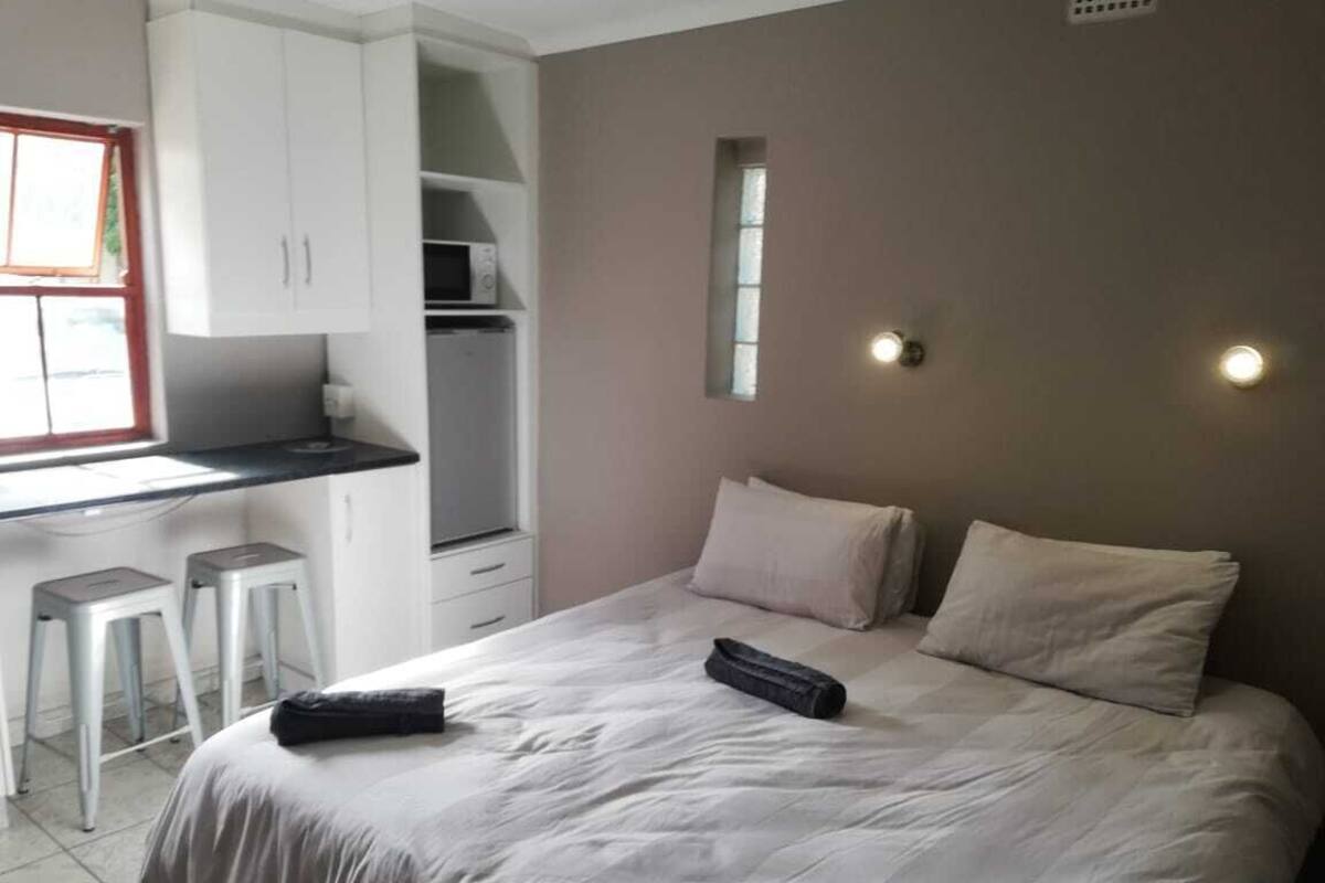Une chambre à coucher avec un lit, des oreillers, un bureau avec une chaise et un four à micro-ondes.