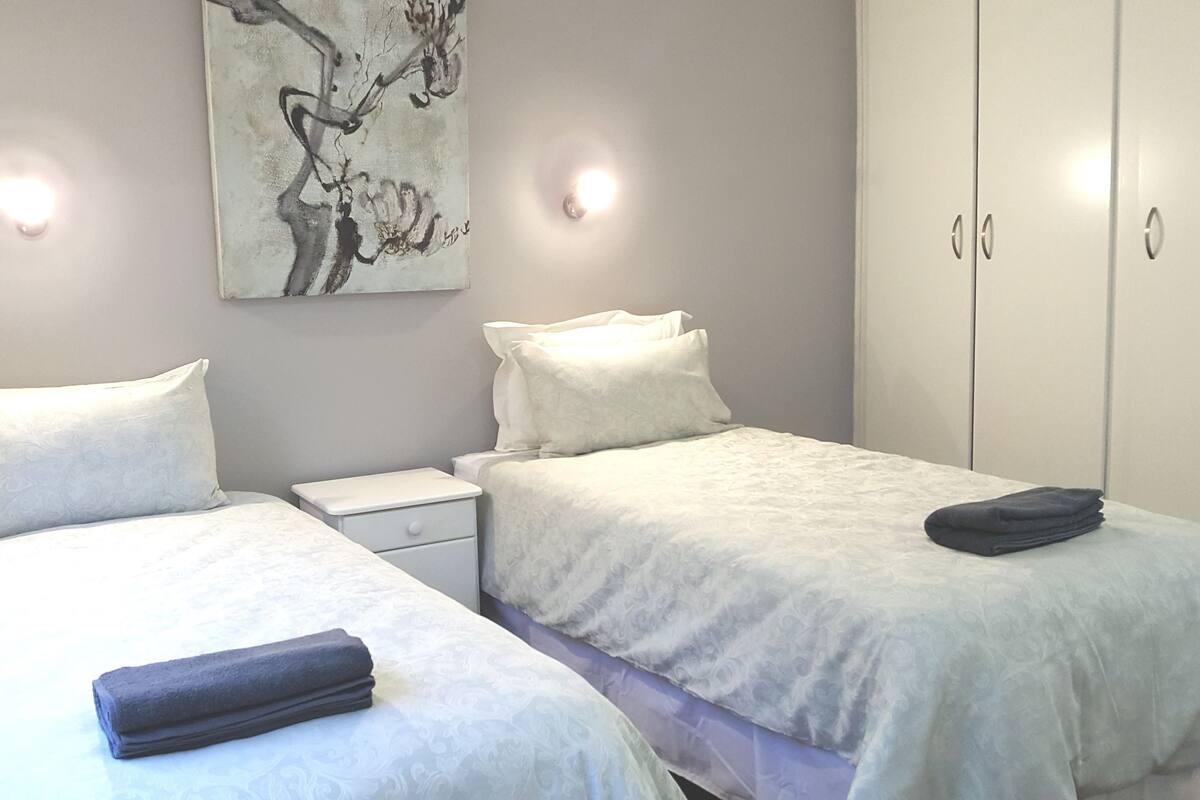 Une chambre d’hôtel avec deux lits, une table de chevet, une œuvre d’art accrochée au mur et une armoire.