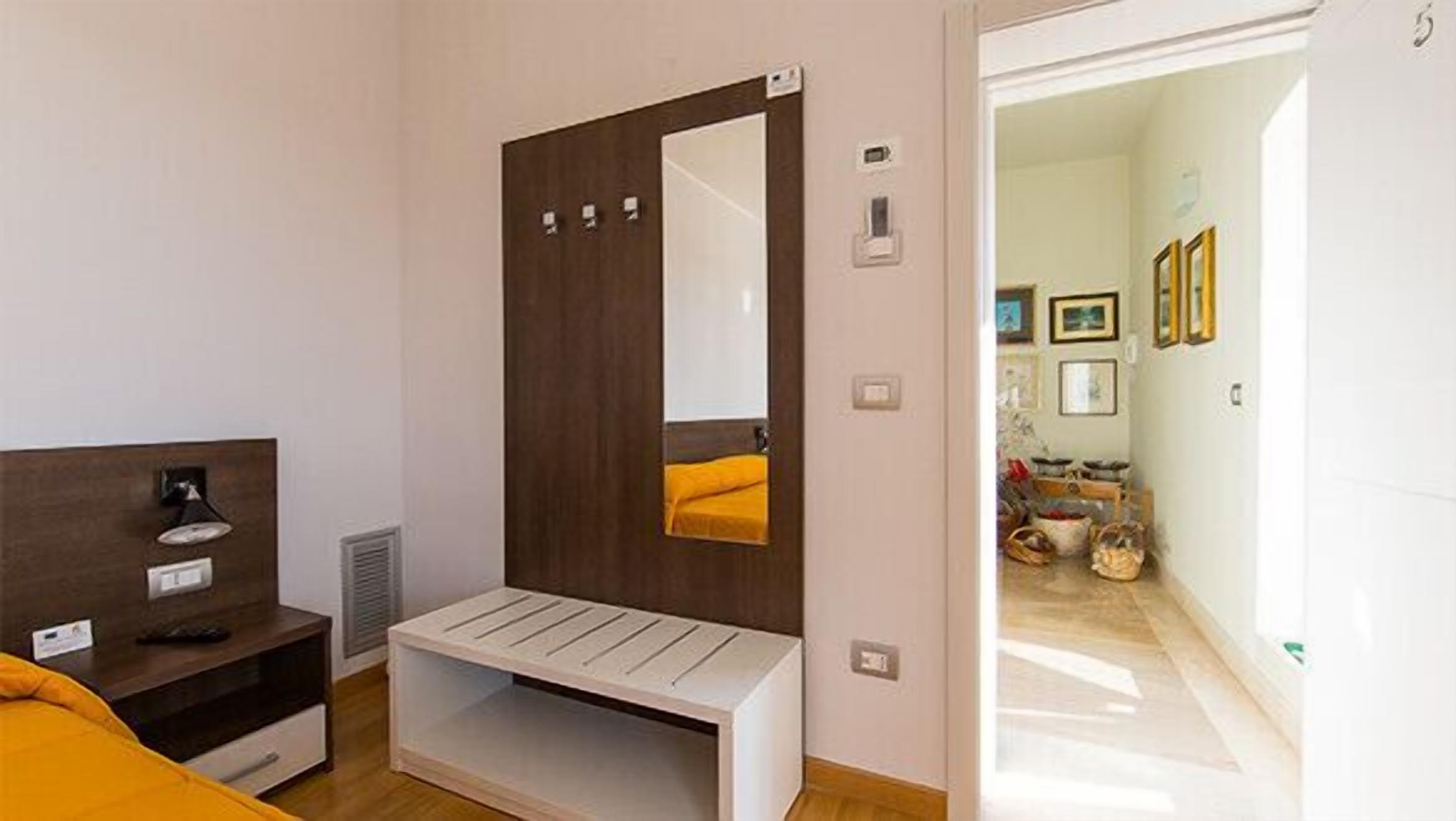 Een moderne slaapkamer met een houten garderobe, een bankje en een bed.