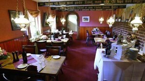 A restaurant with wooden tables and chairs, hanging lamps, and a brick wall. - Gerlev Kro & Hotel (Jægerspris)