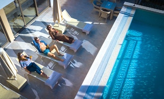 Un área junto a la piscina con sillones de descanso y una piscina.