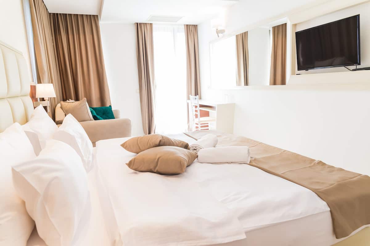 A hotel room with a bed, a chair, a TV, and curtains.