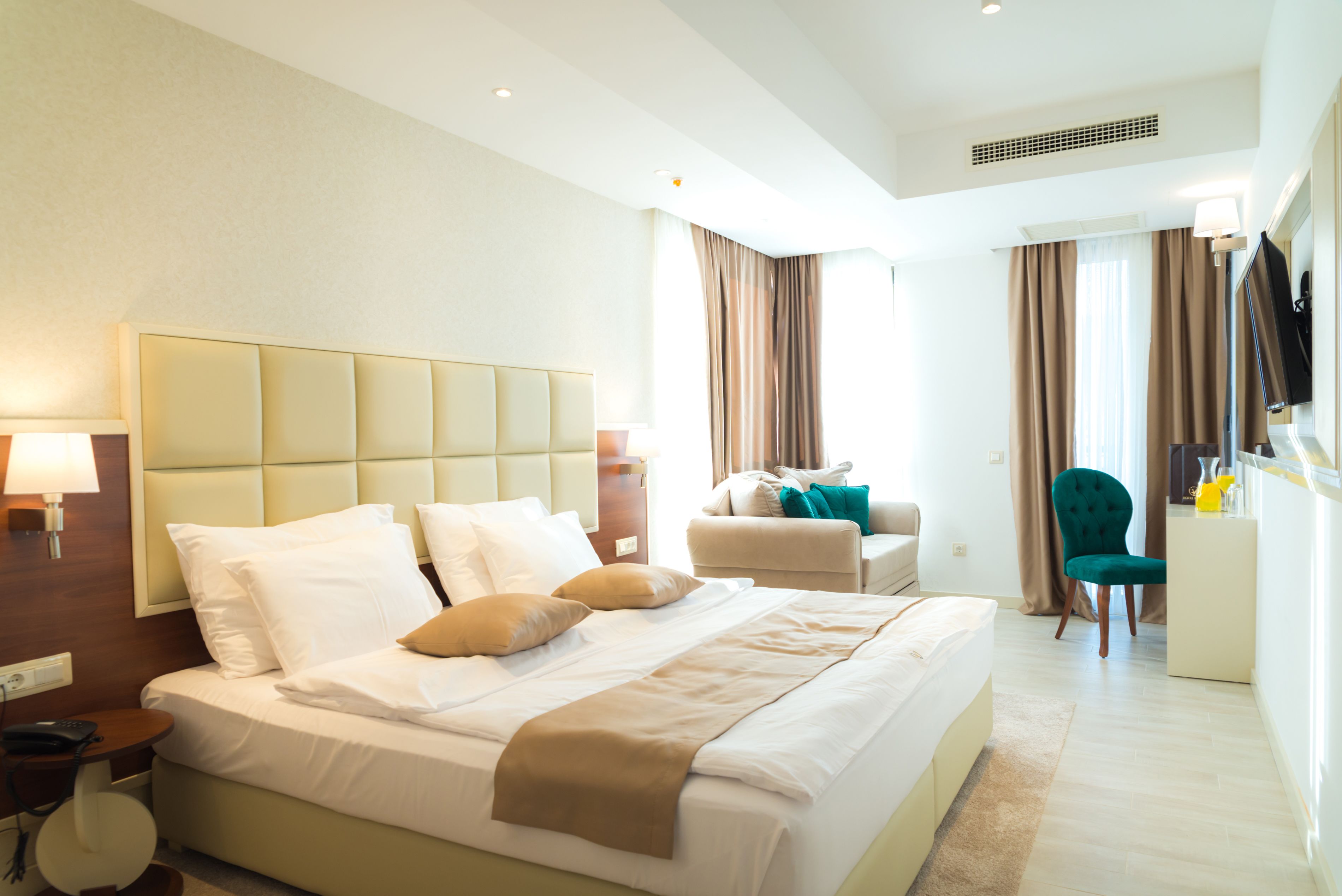 A hotel room with a large bed, a sofa, a desk, and a TV.