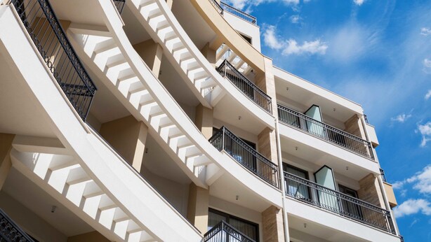 A modern hotel with a curved facade, multiple balconies, and a clear blue sky in the background. - Hotel Kadmo by Aycon (Budva)