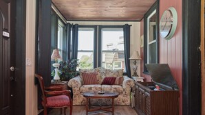 A cozy living room with a floral sofa, wooden coffee table, and a vintage radio cabinet. - The Inn (Gravenhurst)