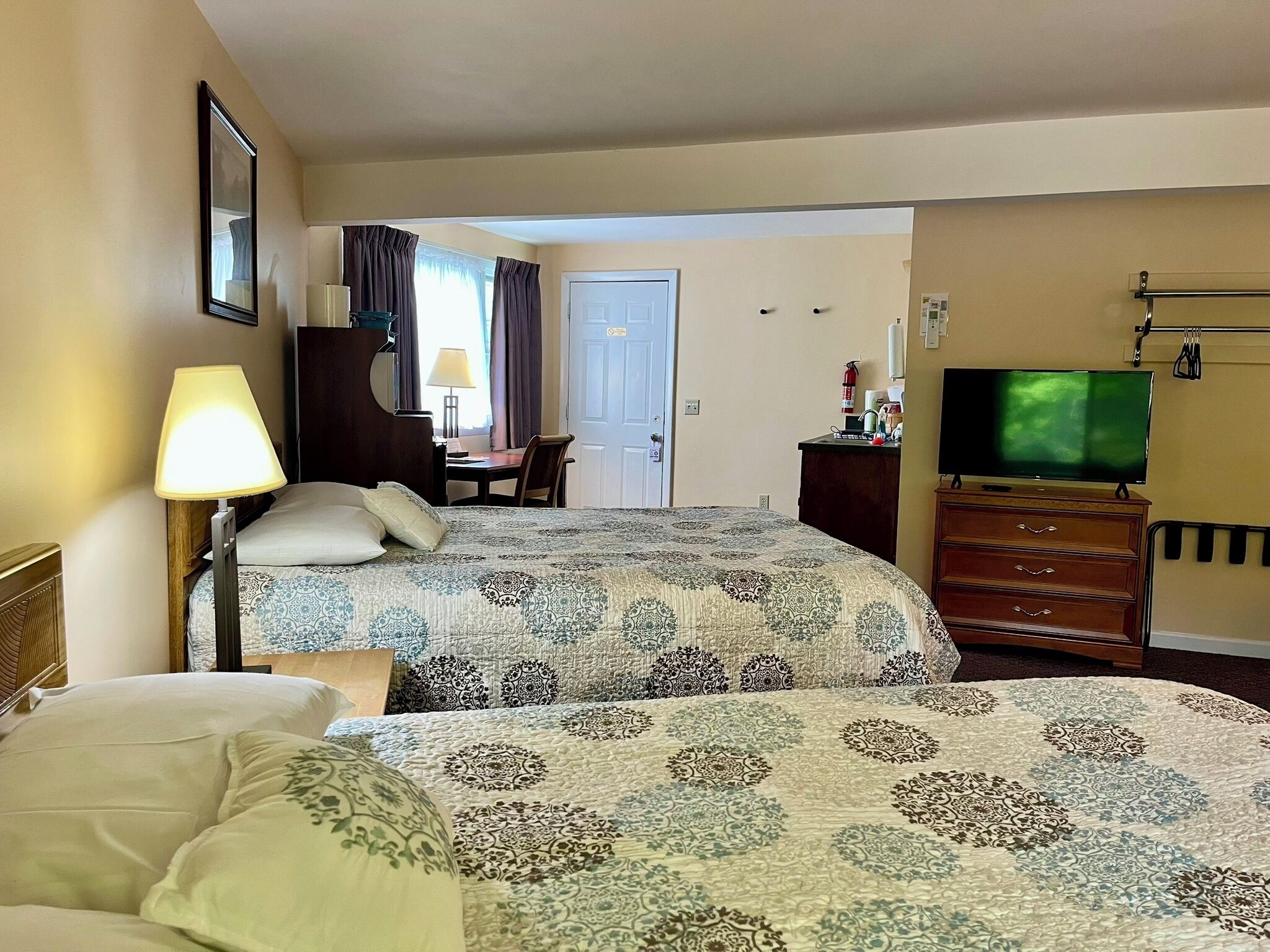 Una habitación de hotel con dos camas, un escritorio, un televisor y un aparador.