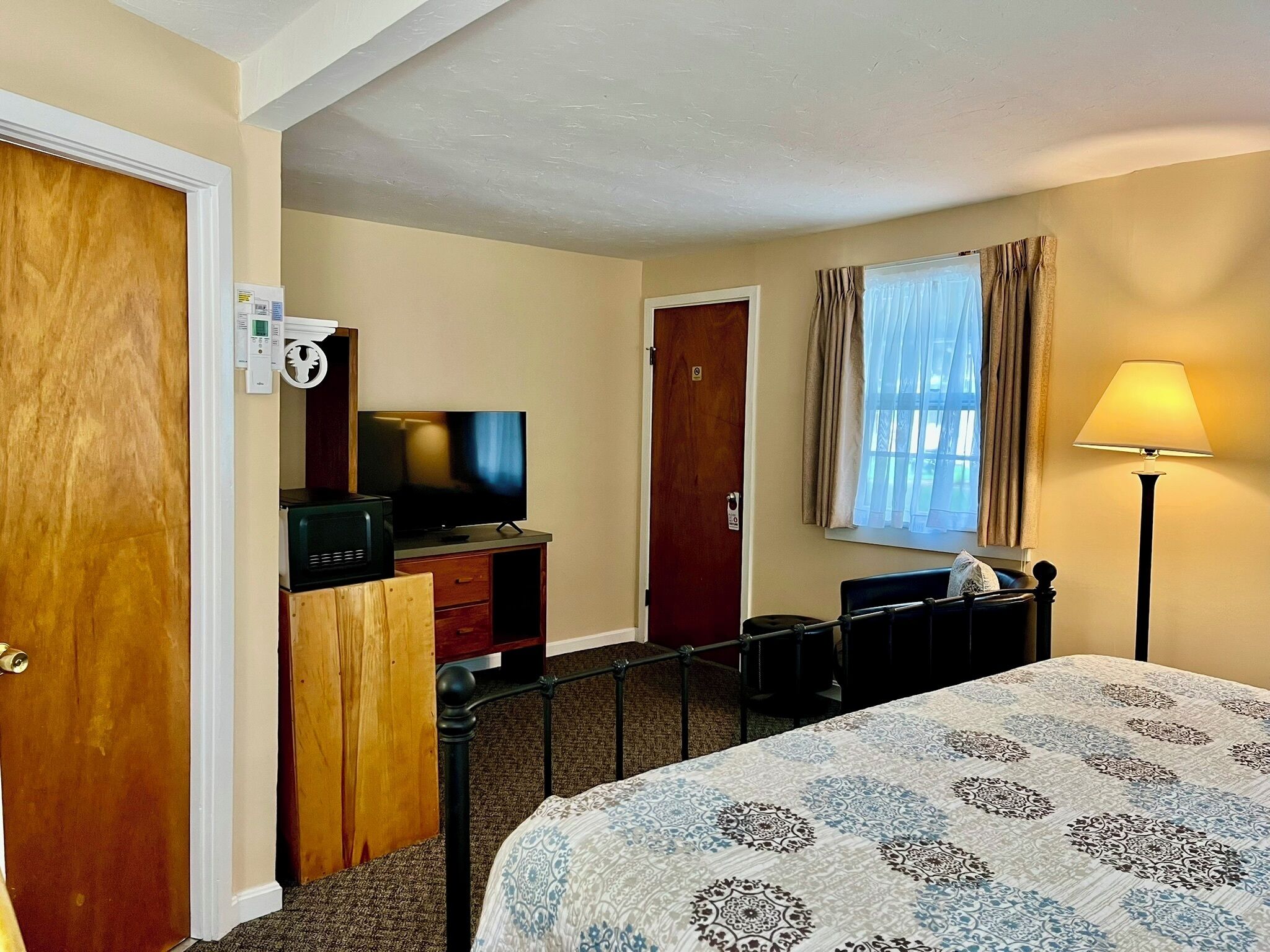 A hotel room with a bed, a television, a desk, and a lamp.