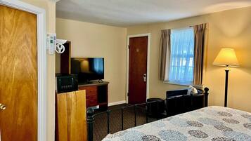 A hotel room with a bed, a television, a desk, and a lamp.