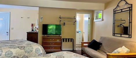 A hotel room with two beds, a TV, a dresser, a sofa, and a mirror.