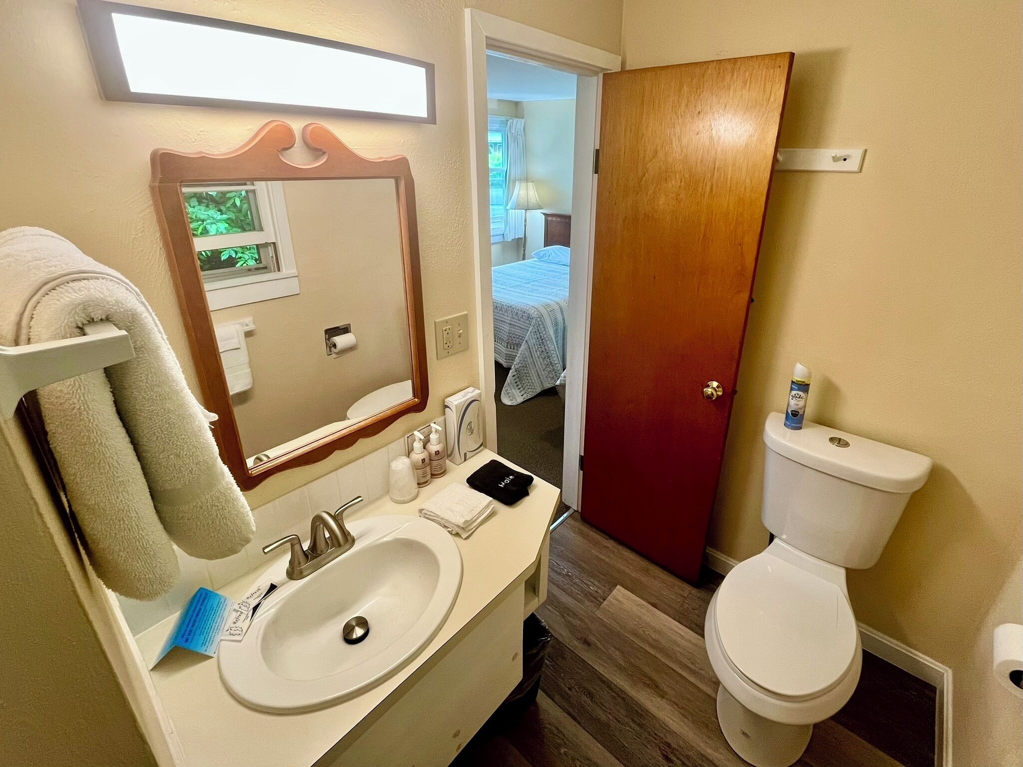A bathroom with a sink, mirror, toilet, and a towel rack.