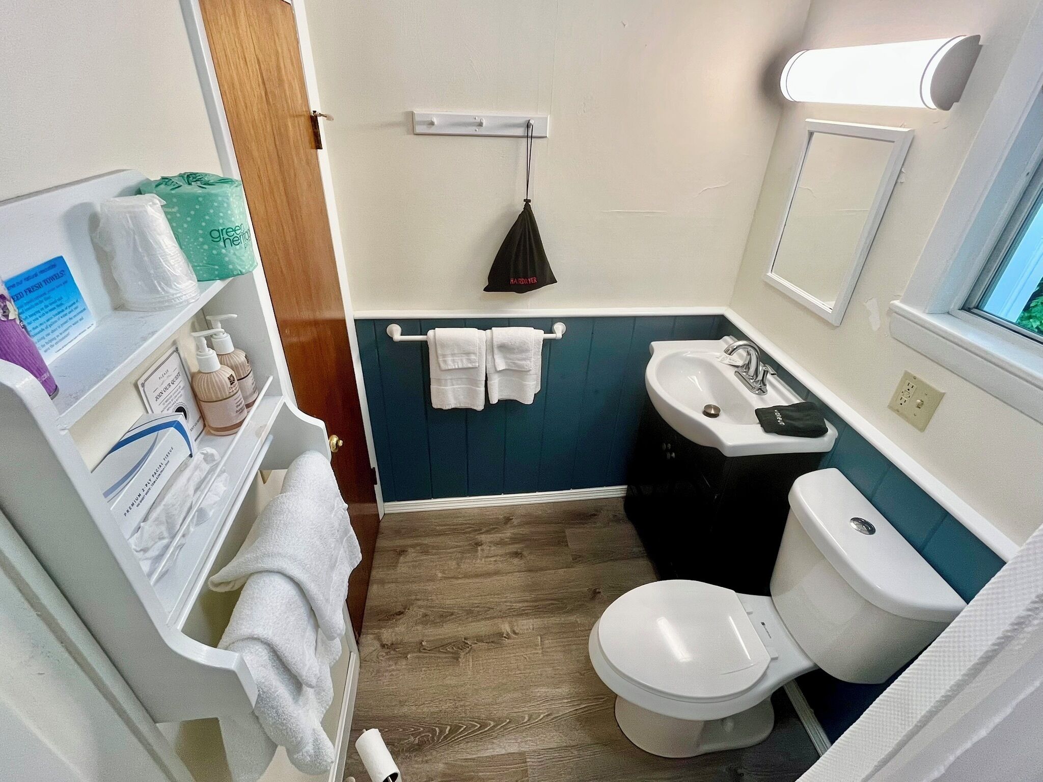 Uma casa de banho compacta com sanita branca, lavatório e um porta-toalhas.