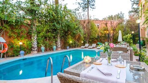 A poolside area with a clear pool, wicker furniture, and a table set for dining.