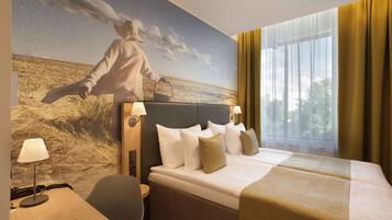 A hotel room with a large bed, two bedside tables, a desk, and a mural of a cowboy on a horse.