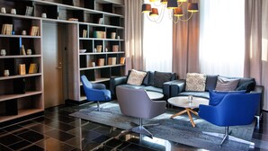 Uma sala de estar moderna com um sofá seccional, poltronas azuis, uma mesa de centro e uma estante repleta de livros.