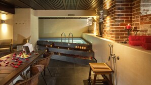 Uma área de spa com hidromassagem, assentos e uma mesa posta com frutas e copos.